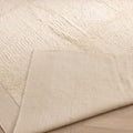 Handwoven white shaggy wool and cotton rug with a thick, textured pile and a smooth, durable backing on a wooden floor.