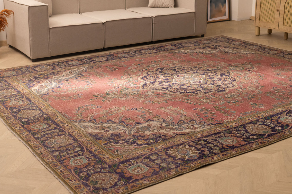 Oversized pink and navy Persian-style wool-cotton rug with intricate floral patterns in a bohemian living room.