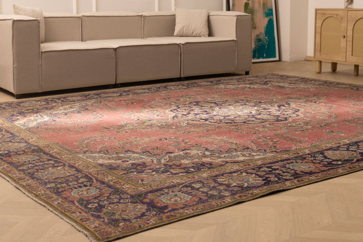 Oversized pink Persian-style wool and cotton area rug with intricate floral patterns in a modern living room setting.