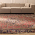 Oversized pink Persian-style wool and cotton area rug with intricate floral patterns in a bohemian living room.