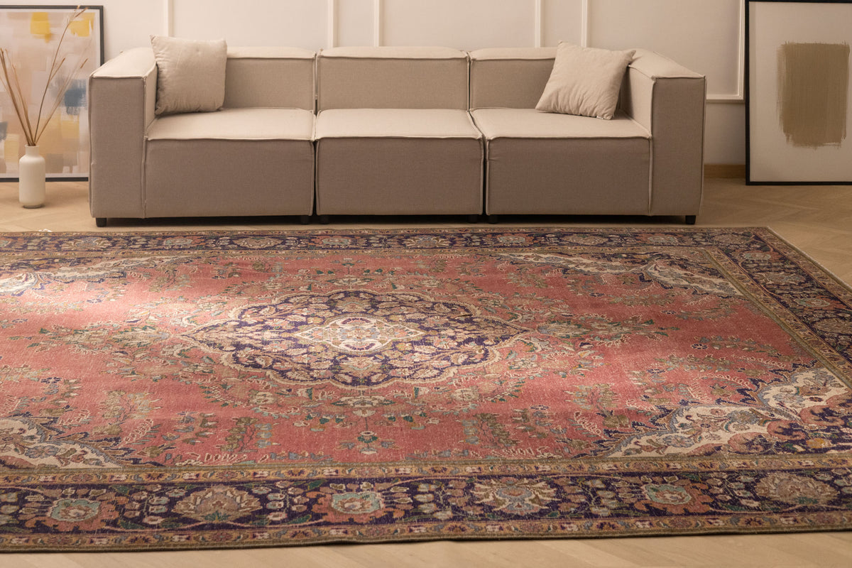 Oversized pink Persian-style wool and cotton area rug with intricate floral patterns in a bohemian living room.