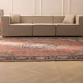 Oversized pink Persian-style wool and cotton area rug with intricate floral patterns in a modern living room.