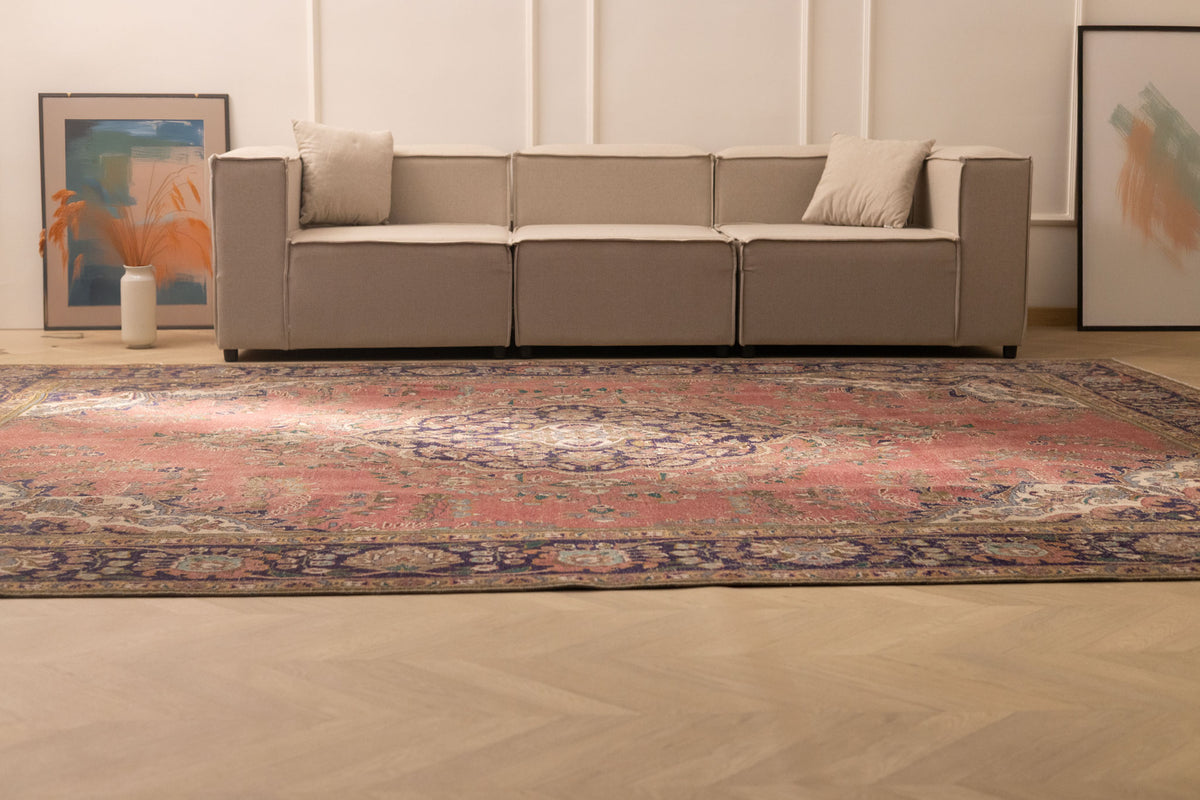 Oversized pink Persian-style wool and cotton area rug with intricate floral patterns in a modern living room.