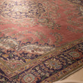Oversized pink Persian-style area rug with intricate floral motifs, handmade from wool and cotton in a traditional bohemian design.