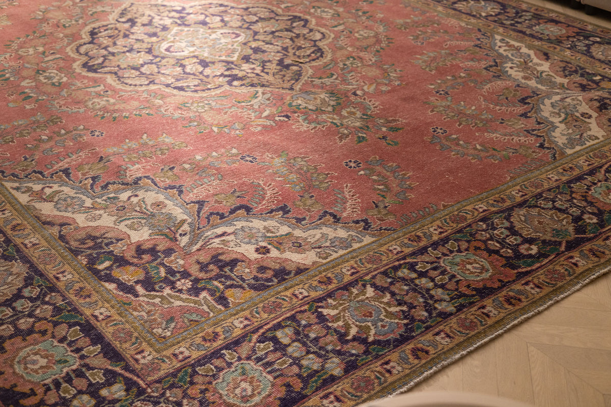 Oversized pink Persian-style area rug with intricate floral motifs, handmade from wool and cotton in a traditional bohemian design.