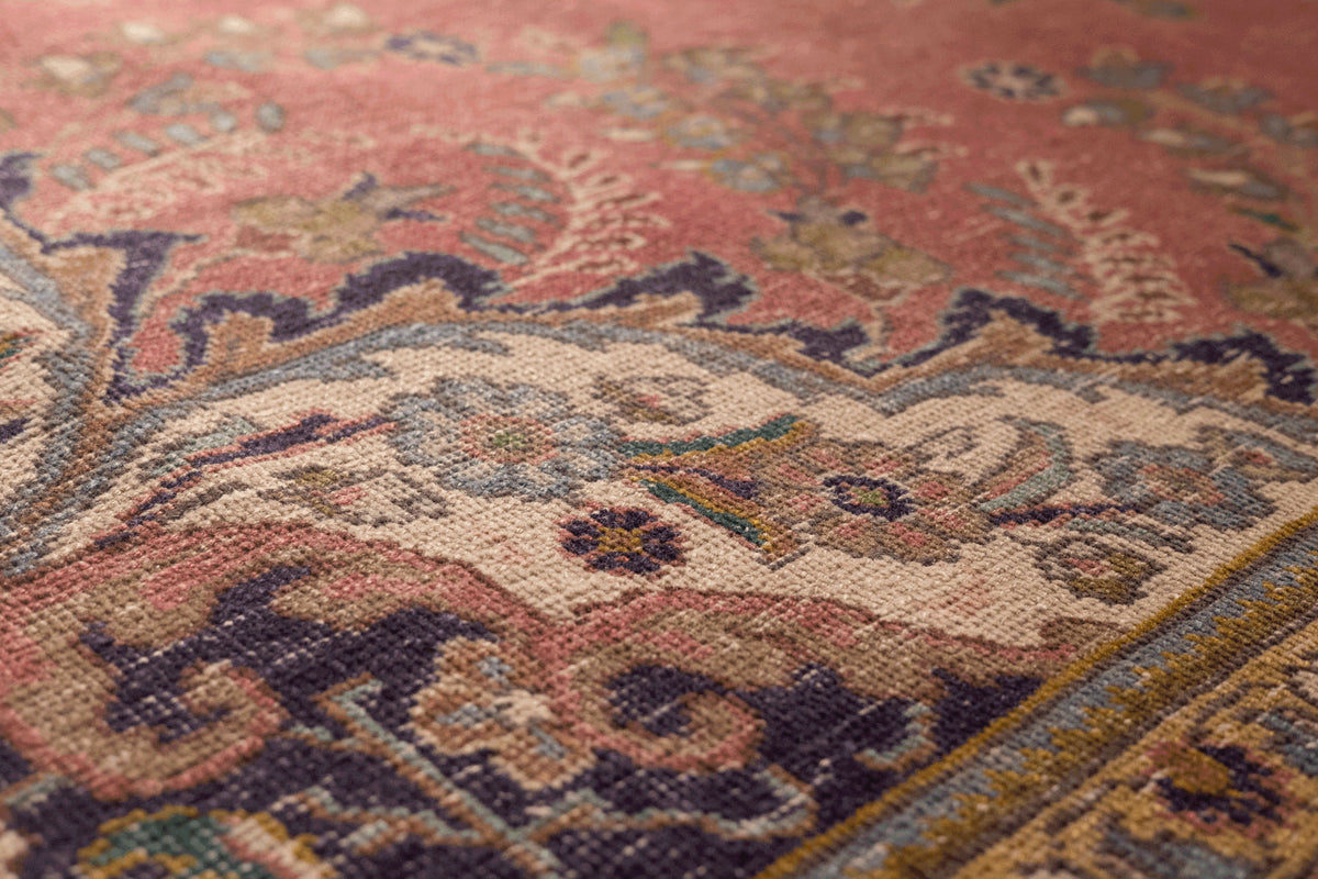 Oversized pink Persian-style area rug with intricate floral motifs, handmade from wool and cotton in a traditional bohemian design.