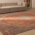 Oversized red Persian-style wool and cotton rug with intricate floral patterns in a bright living room.