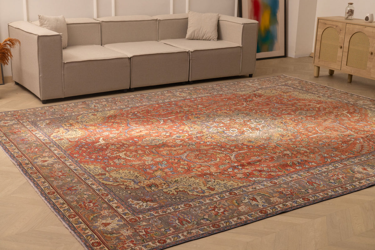 Oversized red Persian-style wool and cotton rug with intricate floral patterns in a bright living room.