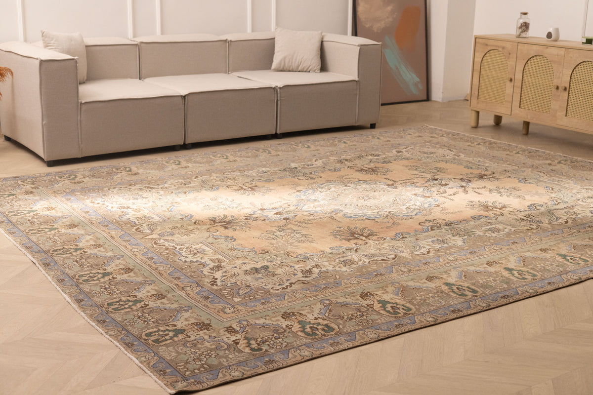 Oversized 10x13 Persian-style wool and cotton rug featuring brown and green floral patterns in a farmhouse living room.