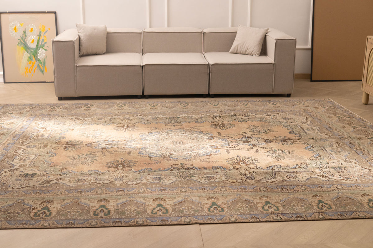 Oversized Persian-style wool and cotton area rug in brown and green with intricate floral motifs in a farmhouse living room.