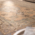 Oversized wool and cotton Persian-style area rug in brown and green with intricate floral motifs and a low pile texture.