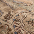 Handmade wool and cotton Persian-style area rug with intricate brown and green floral patterns and low-pile texture.