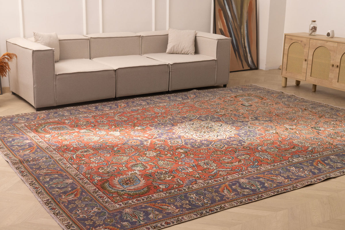 Oversized 9.7x13 ft Persian-style wool and cotton rug with red and navy floral patterns in a bohemian living room.