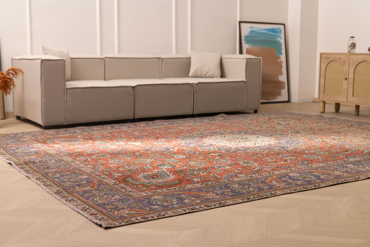 Oversized 9.7x13 ft Persian-style wool and cotton area rug featuring red and navy floral patterns in a living room.