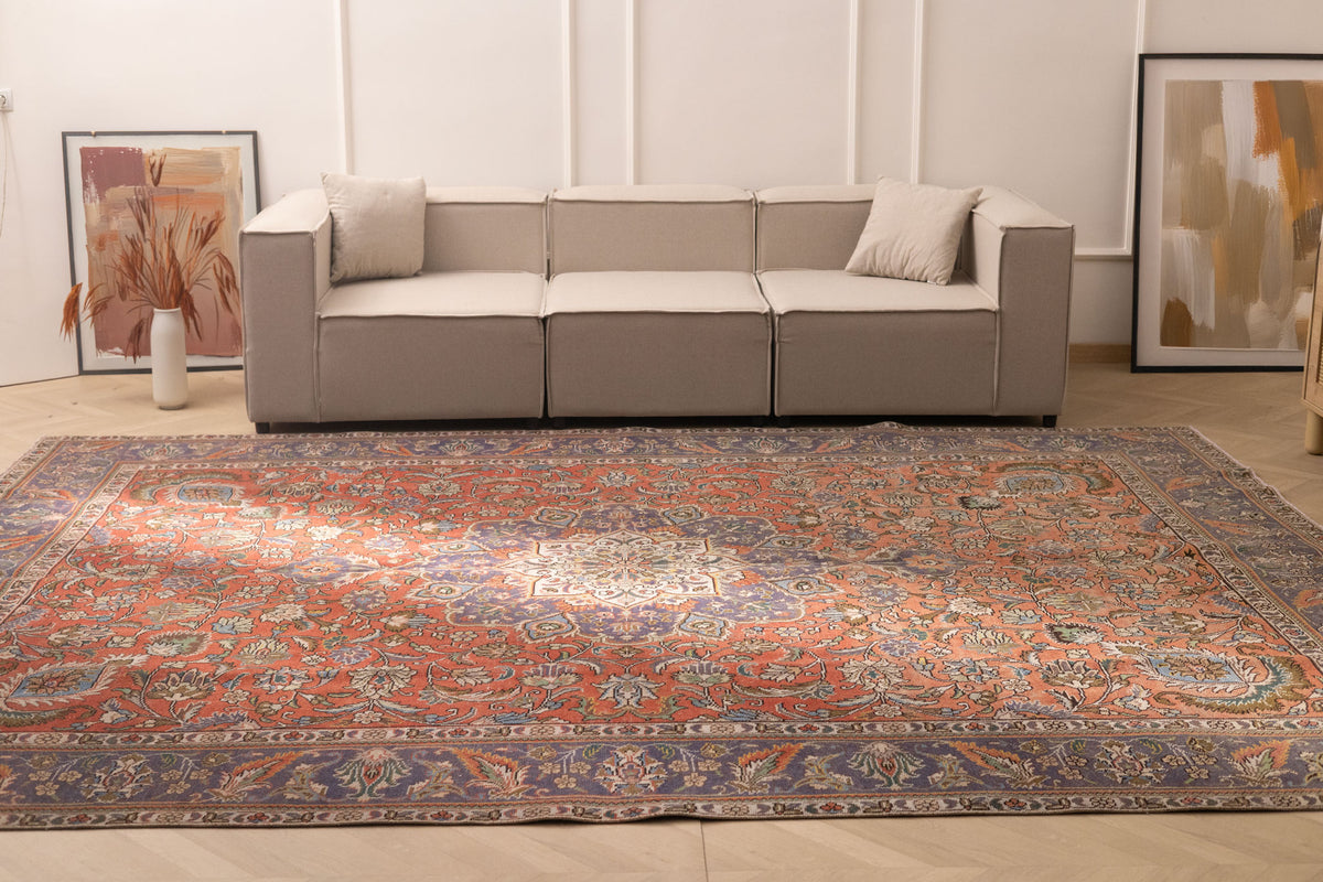 Oversized wool and cotton Persian-style rug in red and navy with intricate floral patterns in a living room.