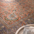Oversized Persian-style wool and cotton area rug featuring red and navy floral patterns in a traditional bohemian design.