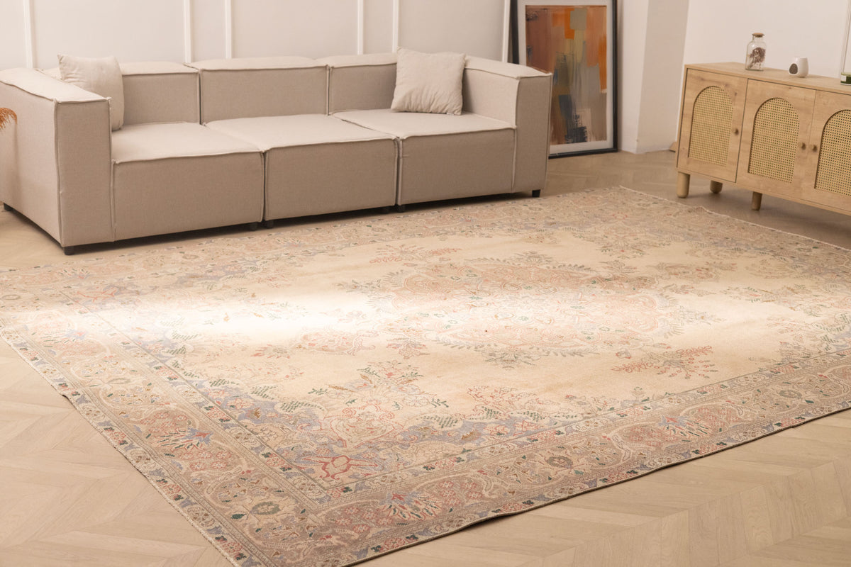 Oversized beige Persian-style wool and cotton rug with intricate floral motifs in a traditional bohemian living room.