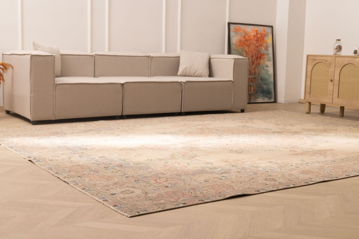 Oversized beige Persian-style wool and cotton area rug with intricate floral motifs in a bright, modern living room.