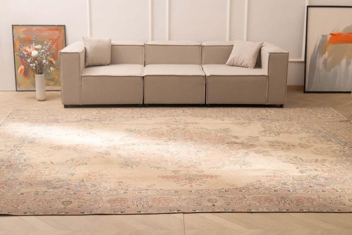 Oversized beige Persian-style wool and cotton area rug with intricate floral motifs in a traditional bohemian living room.