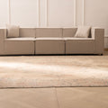 Oversized beige Persian-style wool and cotton area rug with intricate floral motifs in a bright, modern living room.