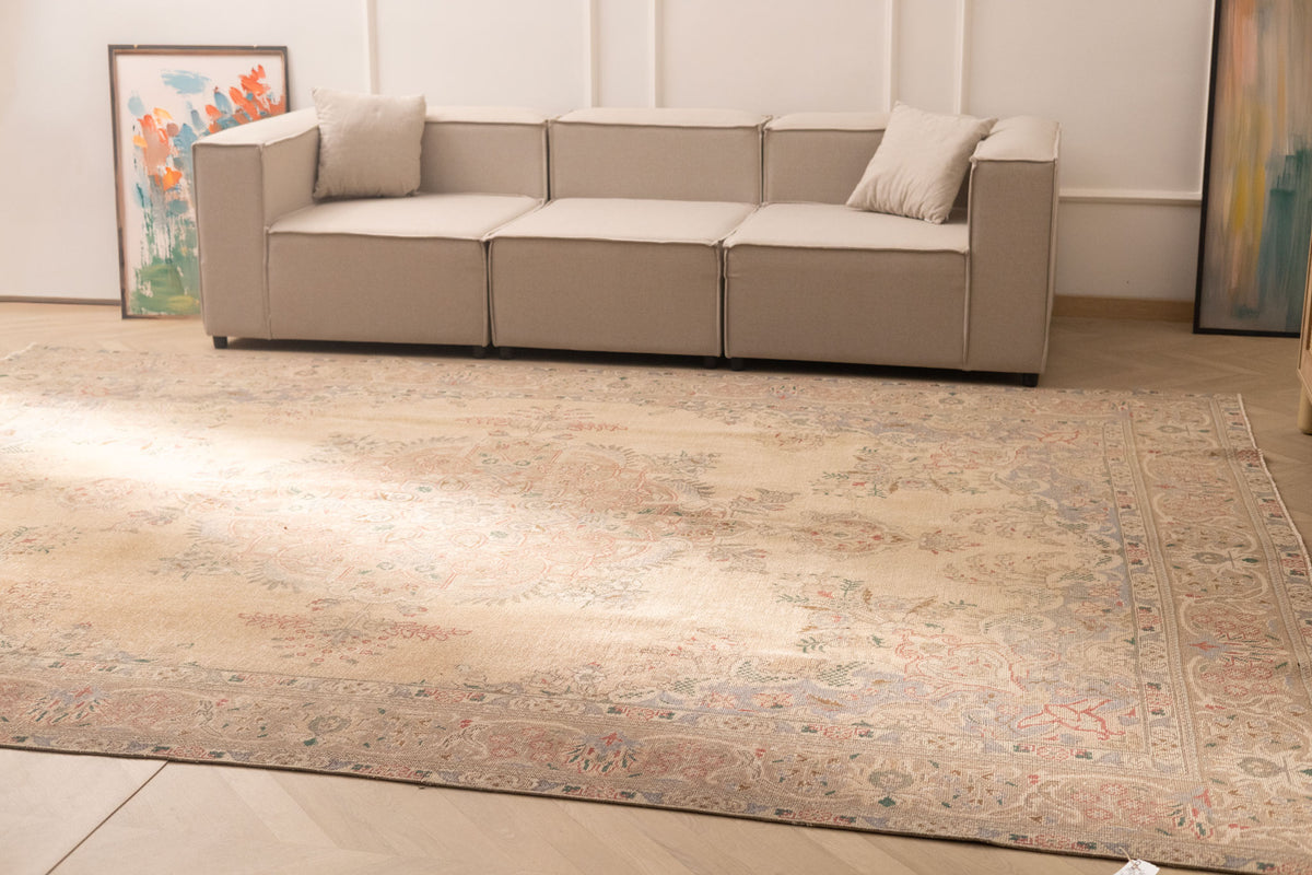 Oversized beige Persian-style wool and cotton area rug with intricate floral motifs in a traditional bohemian living room.