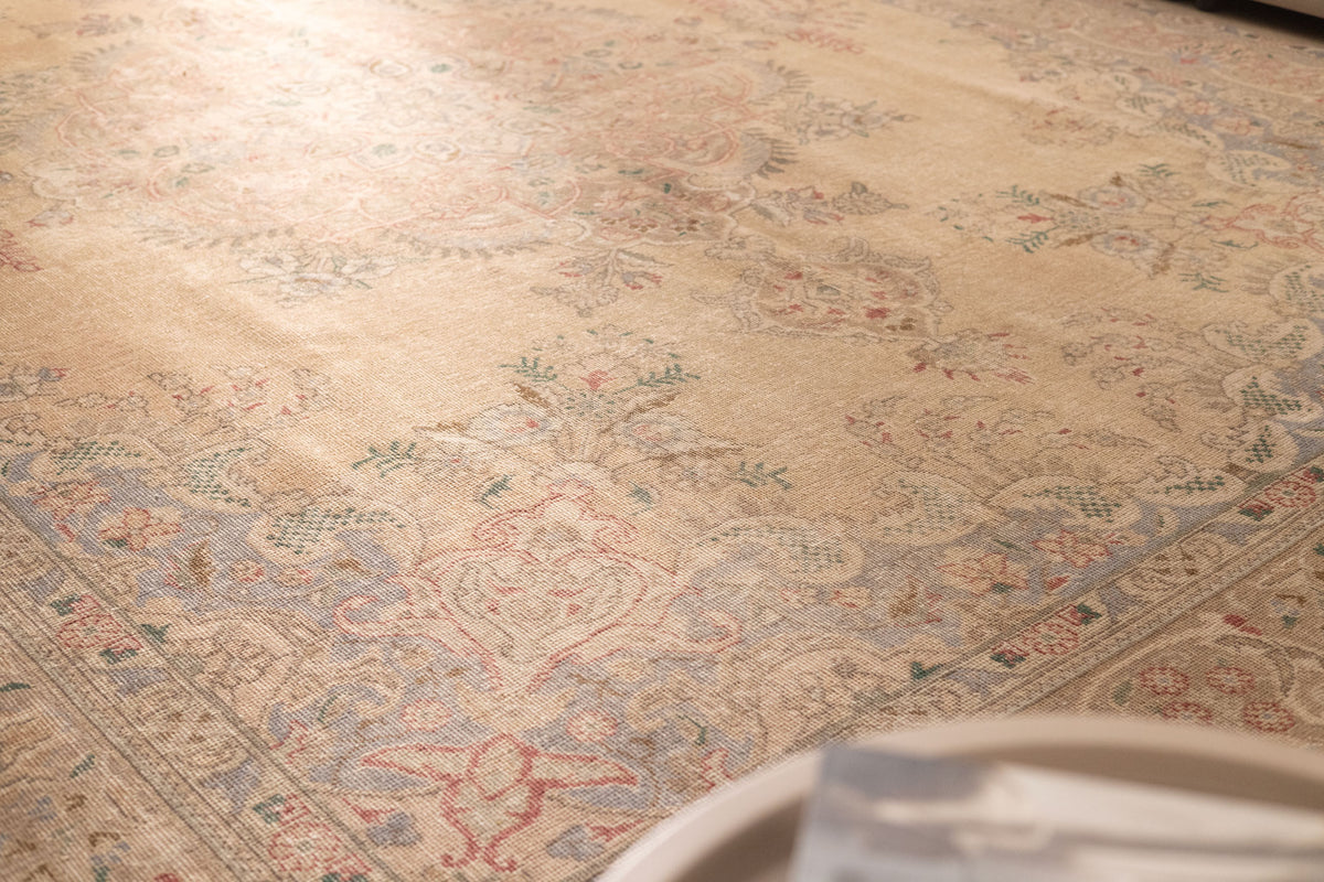 Oversized beige Persian-style wool and cotton area rug featuring intricate floral motifs and traditional bohemian patterns.