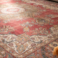 Oversized red Persian-style wool and cotton rug with intricate floral motifs and traditional bohemian patterns.