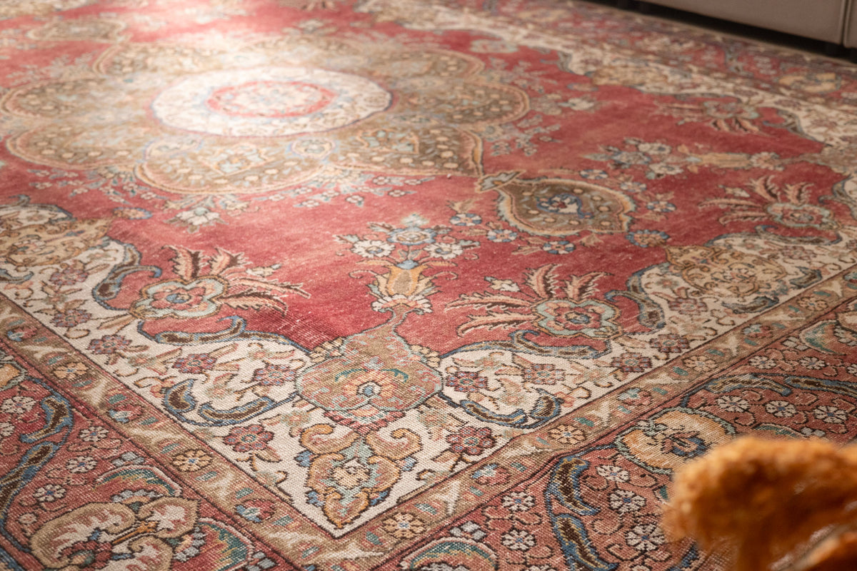 Oversized red Persian-style wool and cotton rug with intricate floral motifs and traditional bohemian patterns.