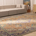 Oversized Persian-style wool and cotton rug with orange and navy floral patterns in a traditional bohemian living room.