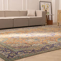Oversized Persian-style wool and cotton rug with orange and navy floral patterns in a bohemian living room.