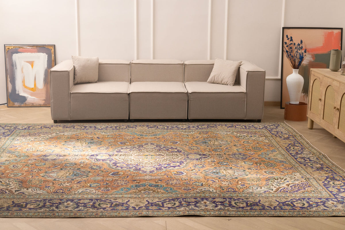 Oversized Persian-style wool and cotton rug featuring orange and navy floral patterns in a traditional bohemian design.