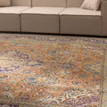 Oversized Persian-style wool and cotton rug with orange and navy floral patterns in a traditional bohemian living room.