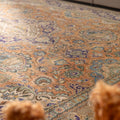 Oversized Persian-style wool and cotton area rug featuring orange and navy floral patterns in a bohemian traditional design.