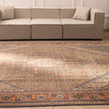 Oversized brown Persian-style wool and cotton rug with intricate floral motifs in a traditional farmhouse living room.