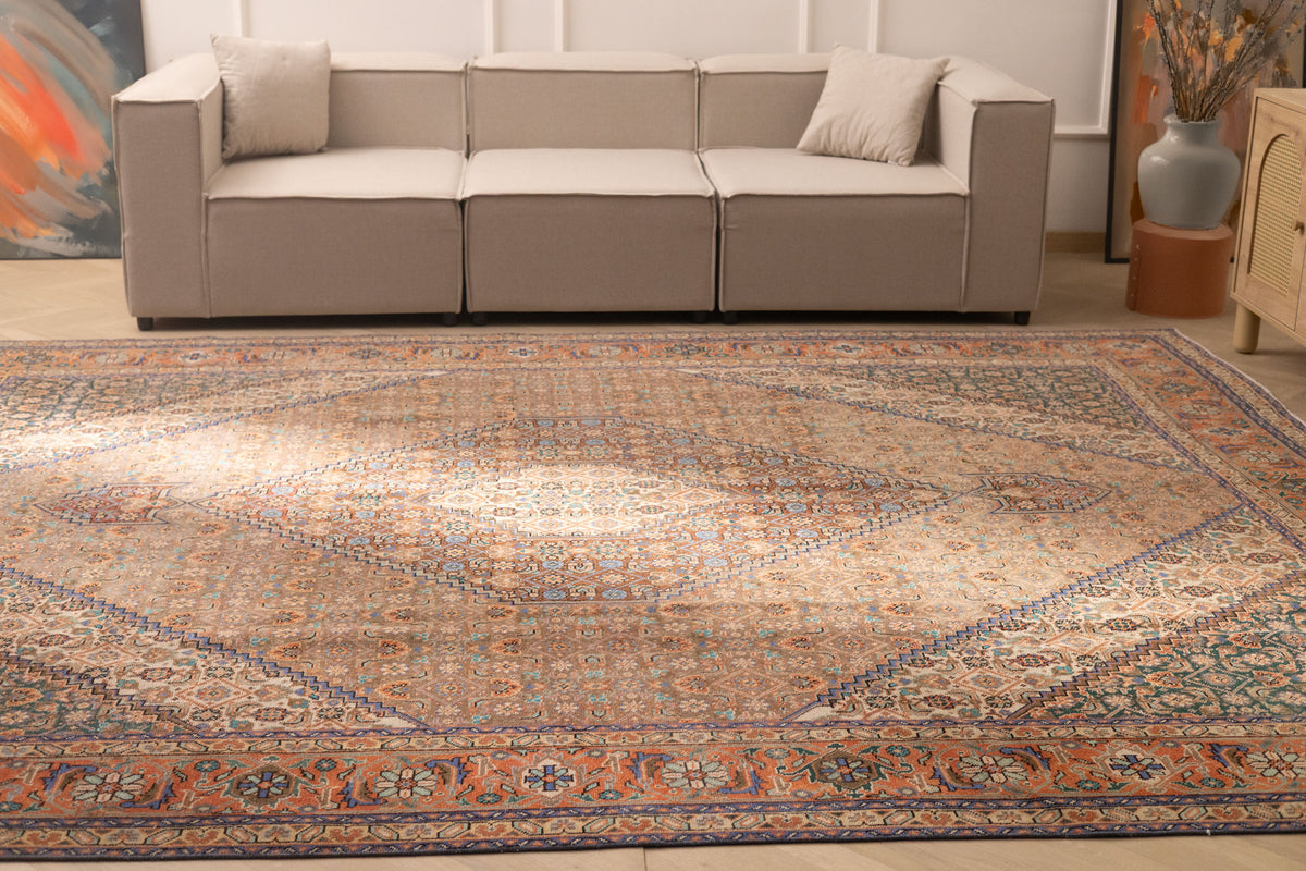 Oversized brown Persian-style wool and cotton rug with intricate floral motifs in a traditional farmhouse living room.