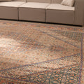Oversized brown Persian-style wool and cotton rug with intricate floral motifs and traditional patterns in a living room.