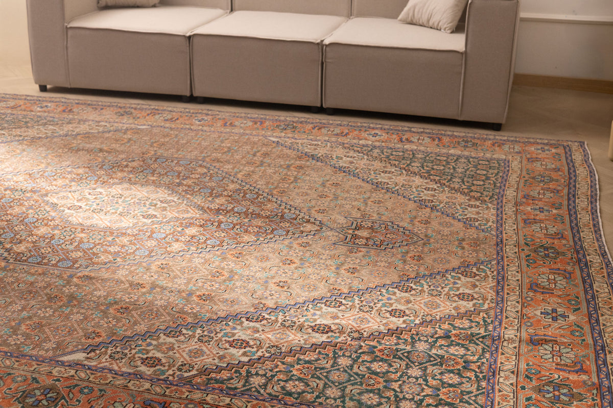 Oversized brown Persian-style wool and cotton rug with intricate floral motifs and traditional patterns in a living room.
