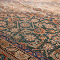 Handmade Persian-style wool and cotton area rug featuring intricate brown and green floral patterns.
