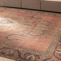 Oversized Persian-style wool and cotton rug with brown floral patterns and traditional motifs in a low pile design.