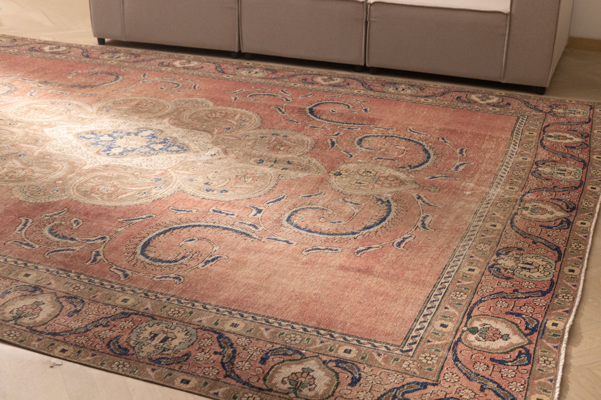 Oversized Persian-style wool and cotton rug with brown floral patterns and traditional motifs in a low pile design.