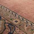 Handmade wool and cotton Persian-style rug featuring brown floral patterns and intricate blue and green border details.