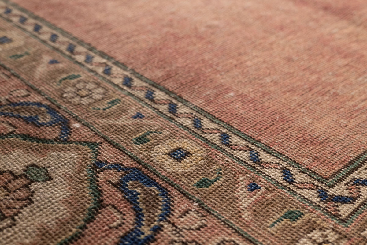 Handmade wool and cotton Persian-style rug featuring brown floral patterns and intricate blue and green border details.
