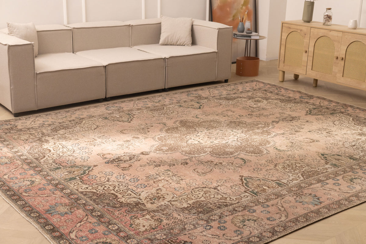 Oversized beige Persian-style wool and cotton area rug with elegant floral motifs in a traditional living room.
