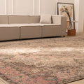 Oversized beige Persian-style wool and cotton area rug with traditional floral patterns in a living room.