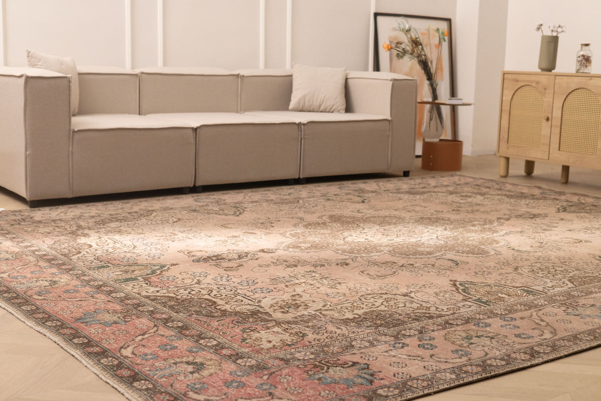 Oversized beige Persian-style wool and cotton area rug with traditional floral patterns in a living room.