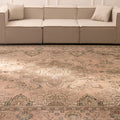 Oversized beige Persian-style wool and cotton area rug featuring traditional floral motifs in a living room setting.