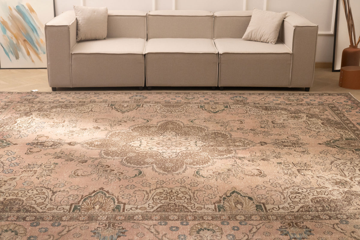Oversized beige Persian-style wool and cotton area rug featuring traditional floral motifs in a living room setting.