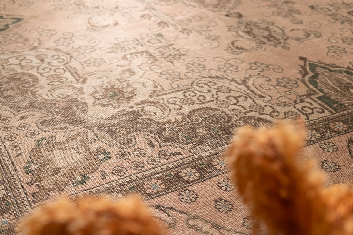 Oversized beige Persian-style wool and cotton rug featuring intricate traditional floral patterns and a low-pile texture.