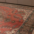 Oversized red Persian-style wool and cotton rug with intricate floral patterns and traditional bohemian motifs.