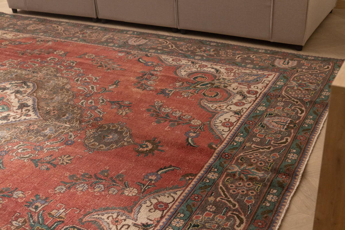 Oversized red Persian-style wool and cotton rug with intricate floral patterns and traditional bohemian motifs.